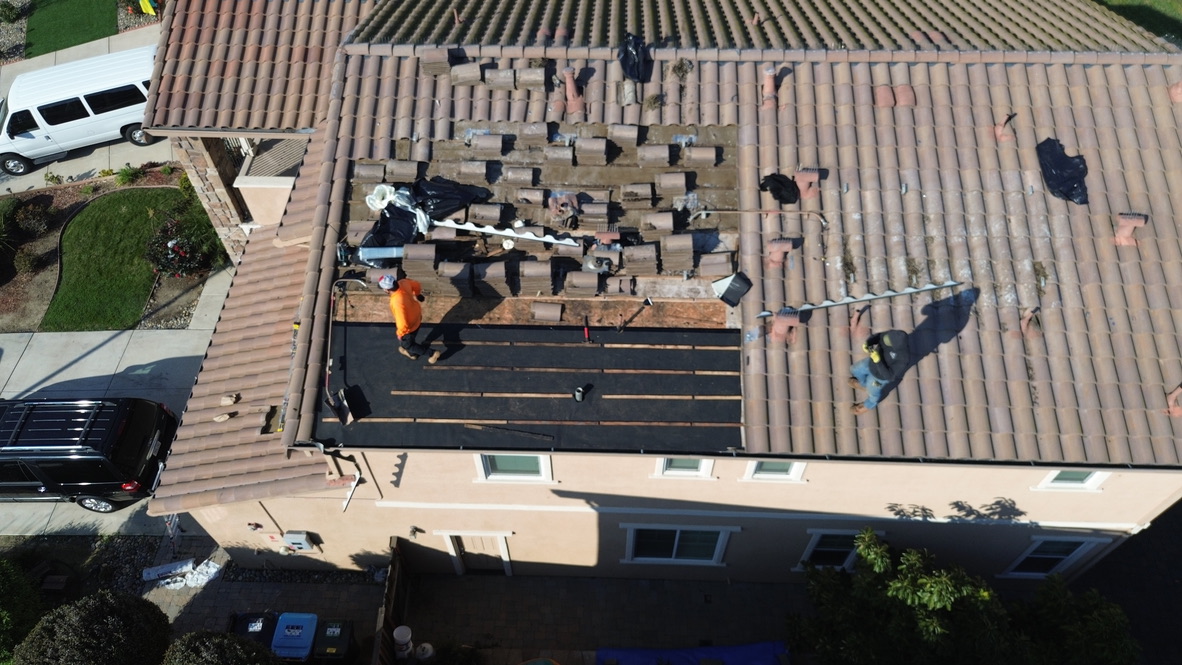 Aerial view of tile roof replacement showing exposed decking and structural inspection